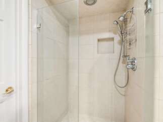 Step into this modern bathroom featuring a spacious glass-enclosed shower with a convenient handheld showerhead and built-in niche for toiletries.