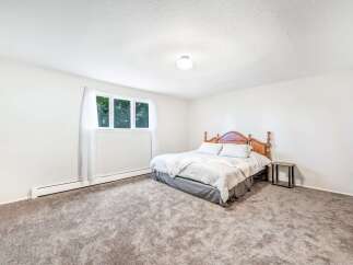 Discover comfort and style in this inviting bedroom, featuring a plush carpet and a classic wooden bed frame.