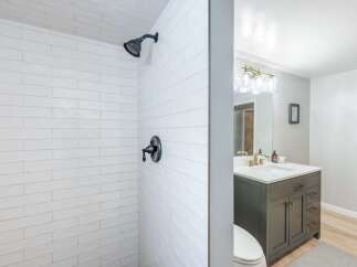 This modern bathroom features a sleek white subway tile shower with a dark matte showerhead and faucet.