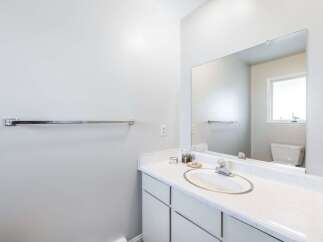 This bathroom features a spacious vanity with a white countertop and a modern sink, complemented by a large mirror reflecting the room.