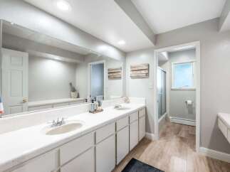 This spacious bathroom features a double vanity with ample counter space and storage, perfect for any household.