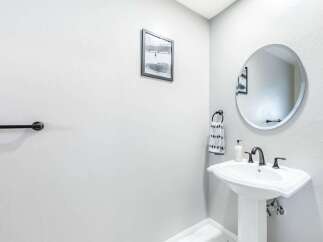 This powder room features a sleek pedestal sink with a modern faucet and a decorative towel ring.