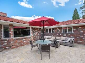 Enjoy outdoor living with this spacious patio featuring a large red umbrella for shade and comfortable seating.