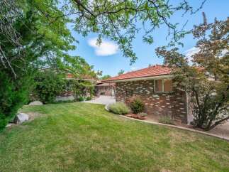 Discover this charming brick home featuring a spacious backyard with a well-maintained lawn and mature trees.
