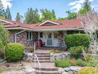 Charming brick home featuring a welcoming red-tiled roof and a picturesque stone pathway leading to the entrance.