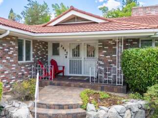Charming brick home with a welcoming covered porch and a beautiful tile roof.