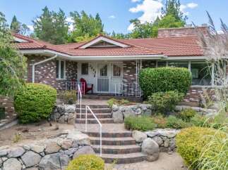 Charming brick home with a welcoming red tile roof and a picturesque stone pathway leading to the entrance.