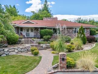 Discover this charming brick home featuring a welcoming red tile roof and a beautifully landscaped yard.