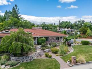 Discover this charming brick home featuring a durable red tile roof and lush landscaping.