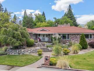 Discover this charming brick home featuring a welcoming entryway with a red chair and a tiled roof.