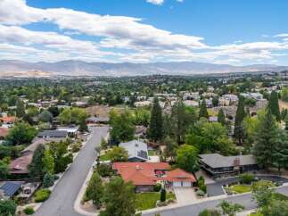 Discover this stunning aerial view of a suburban neighborhood nestled amidst lush greenery and rolling hills.