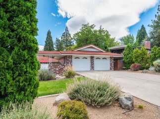 This charming single-family home features a classic brick exterior with a red tile roof, complemented by a well-maintained lawn and mature landscaping.