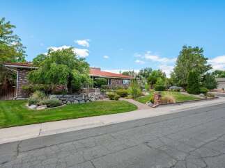 Discover this charming brick home featuring a beautifully landscaped yard with mature trees and a stone retaining wall.