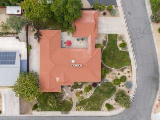 Discover this stunning property from an aerial perspective, showcasing a beautifully landscaped yard with lush green grass and mature trees.