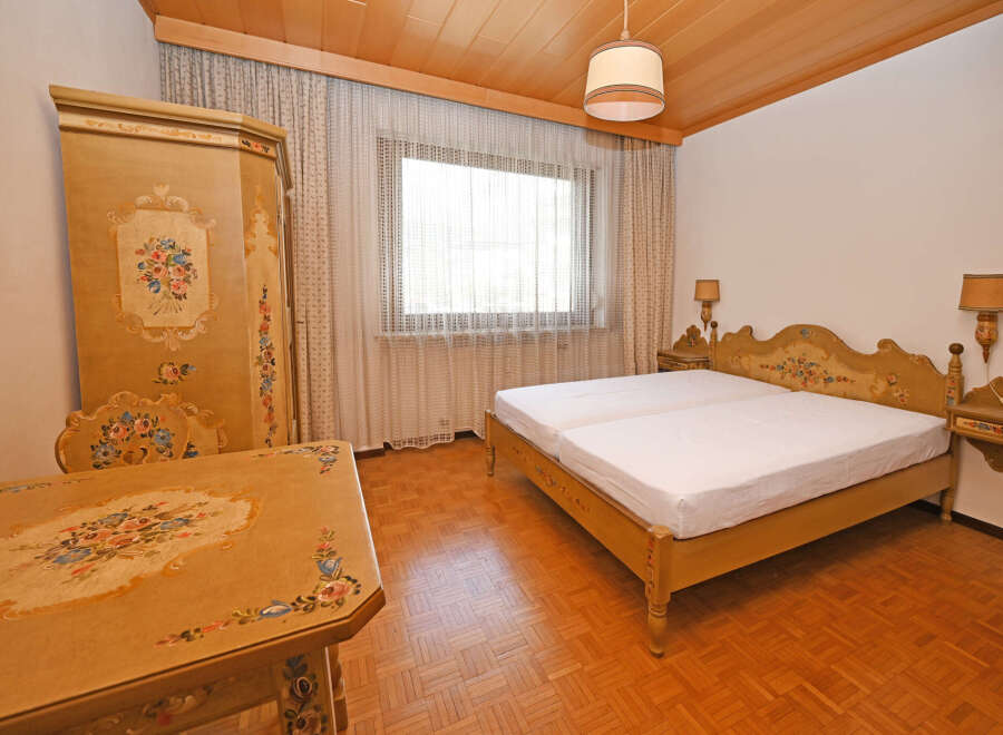 Charming bedroom featuring a beautifully ornate, hand-painted wardrobe and matching bedside tables.