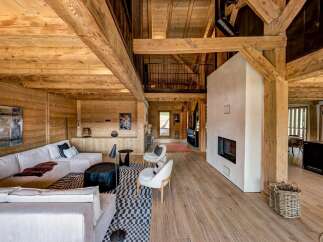 Experience luxury mountain living in this stunning log cabin featuring a spacious open-plan living area with a modern fireplace and ample natural light.