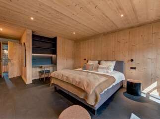 Experience rustic luxury in this charming bedroom, featuring warm, natural wood paneling on the walls and ceiling.