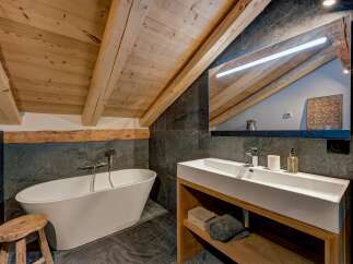 Experience rustic luxury in this stunning bathroom, featuring a freestanding bathtub and a sleek modern vanity.