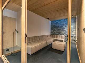 Experience ultimate relaxation in this modern lounge area, featuring a spacious sectional sofa and a cozy ottoman, perfect for unwinding.