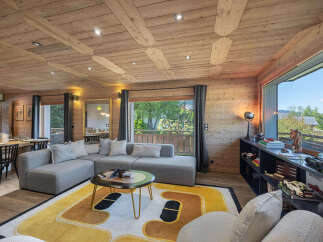 Experience luxurious alpine living in this stunning property featuring a spacious living area with a modern sectional sofa and a unique, eye-catching rug.