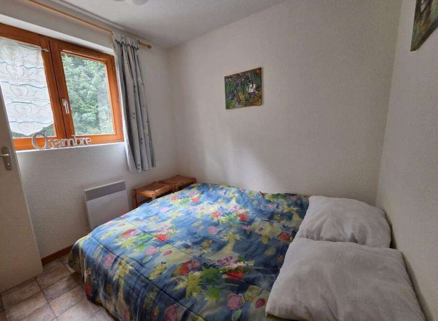 This cozy bedroom features a comfortable double bed adorned with a vibrant floral duvet, perfect for a restful night's sleep.