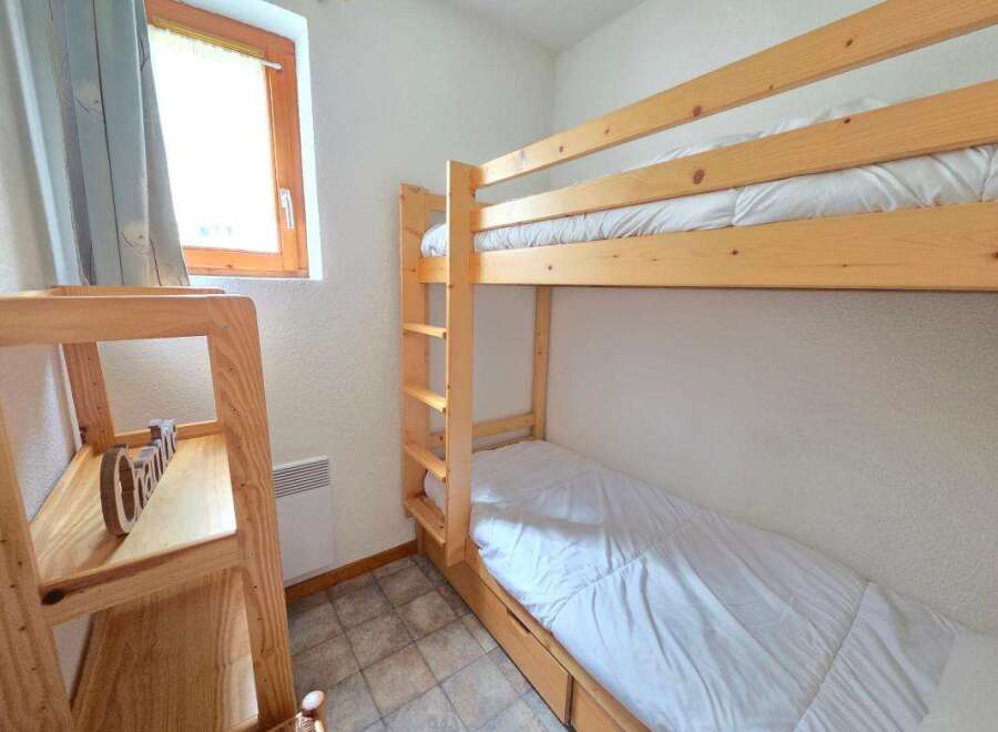 This cozy bedroom features a space-saving bunk bed with white linens, perfect for accommodating guests or children.