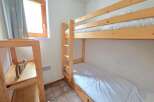 This cozy bedroom features a space-saving bunk bed with white linens, perfect for accommodating guests or children.