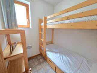 This cozy bedroom features a space-saving bunk bed with white linens, perfect for accommodating guests or children.