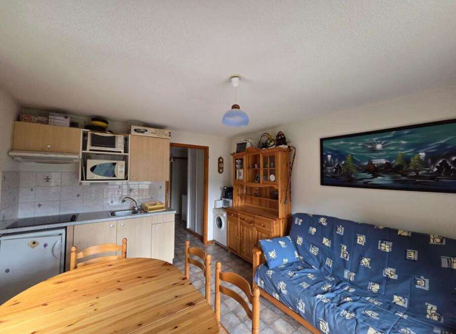 Discover this charming studio apartment featuring a compact kitchen equipped with essential appliances and ample cabinet space.