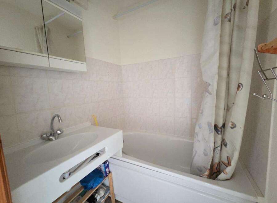 This bathroom features a clean white sink with a modern chrome faucet, complemented by a large mirrored cabinet above.