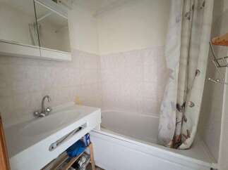 This bathroom features a clean white sink with a modern chrome faucet, complemented by a large mirrored cabinet above.