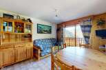 Charming mountain retreat featuring a cozy living area with a blue patterned sofa and a rustic wooden dining table.