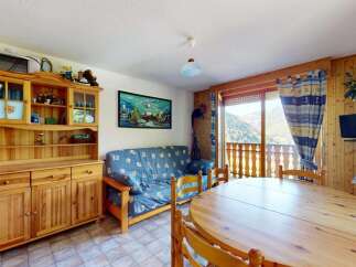 Charming mountain retreat featuring a cozy living area with a blue patterned sofa and a rustic wooden dining table.