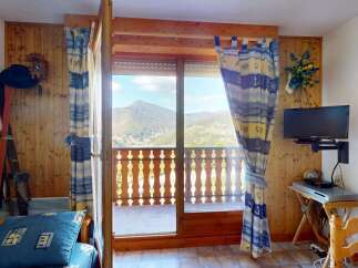 Experience breathtaking mountain views from this charming property, featuring a cozy living space with wooden accents and a private balcony perfect for enjoying the scenery.