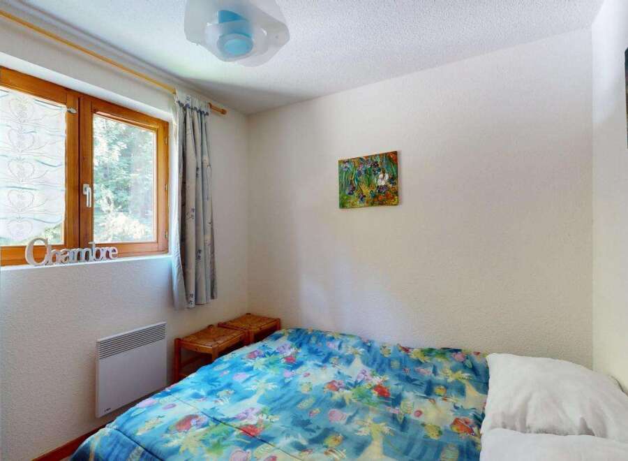 Discover this charming bedroom featuring a comfortable bed adorned with a vibrant, nature-inspired duvet.