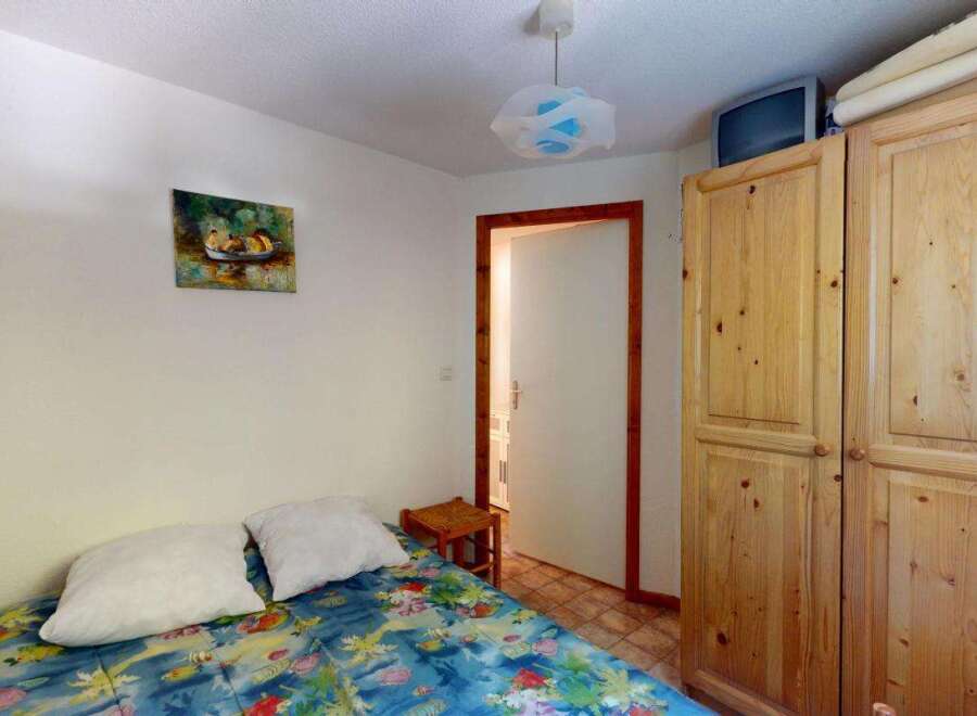 Discover this charming bedroom featuring a comfortable bed adorned with a vibrant, floral-patterned duvet and two plush pillows.