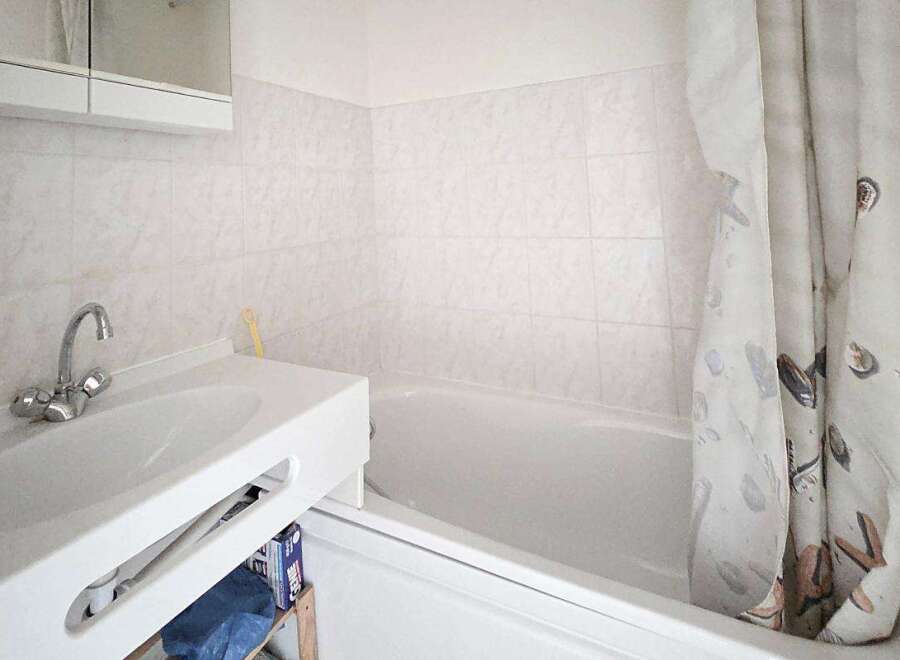 This bathroom features a clean white sink with a modern chrome faucet, complemented by tiled walls for a fresh look.