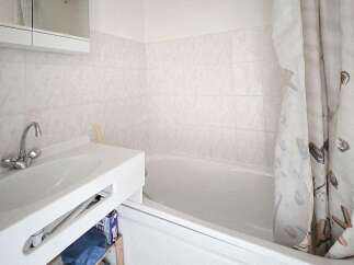 This bathroom features a clean white sink with a modern chrome faucet, complemented by tiled walls for a fresh look.
