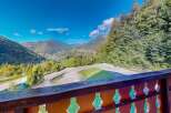 Experience breathtaking mountain views from this property, featuring a spacious balcony overlooking a scenic valley and surrounding evergreen forests.