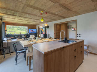 Experience modern alpine living in this stunning open-plan space, featuring a sleek kitchen island with a built-in sink and ample cabinetry.