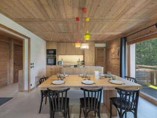 Experience rustic charm and modern convenience in this inviting dining area, featuring a spacious wooden table set for a meal.