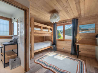 Experience cozy mountain living in this charming bedroom featuring a rustic wooden bunk bed and a large window with stunning alpine views.