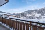 Experience the ultimate winter wonderland from this charming balcony, offering breathtaking panoramic views of snow-covered mountains and a picturesque village nestled in the valley.