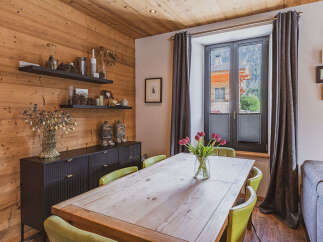 Experience cozy mountain living in this charming dining area, featuring warm wood paneling and a rustic wooden table perfect for family meals.