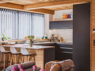 Experience modern living in this stylish kitchen featuring sleek dark cabinetry and a chic tiled backsplash.