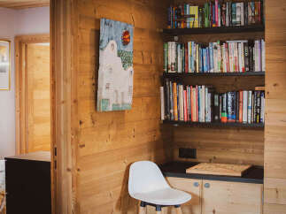 Experience cozy living in this charming room featuring warm wood paneling and a built-in bookshelf filled with a diverse collection of literature.