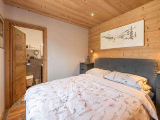 Experience cozy mountain living in this charming bedroom featuring warm wood paneling on the walls and ceiling.