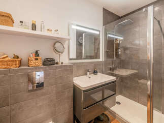 This modern bathroom features a sleek vanity with ample storage, a spacious walk-in shower with a rainfall showerhead, and a large illuminated mirror.