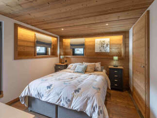 Experience rustic charm in this cozy bedroom, featuring warm wood paneling on the walls and ceiling.