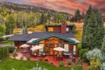 Experience luxury mountain living in this stunning home, featuring expansive windows that showcase breathtaking sunset views and a vibrant sky.